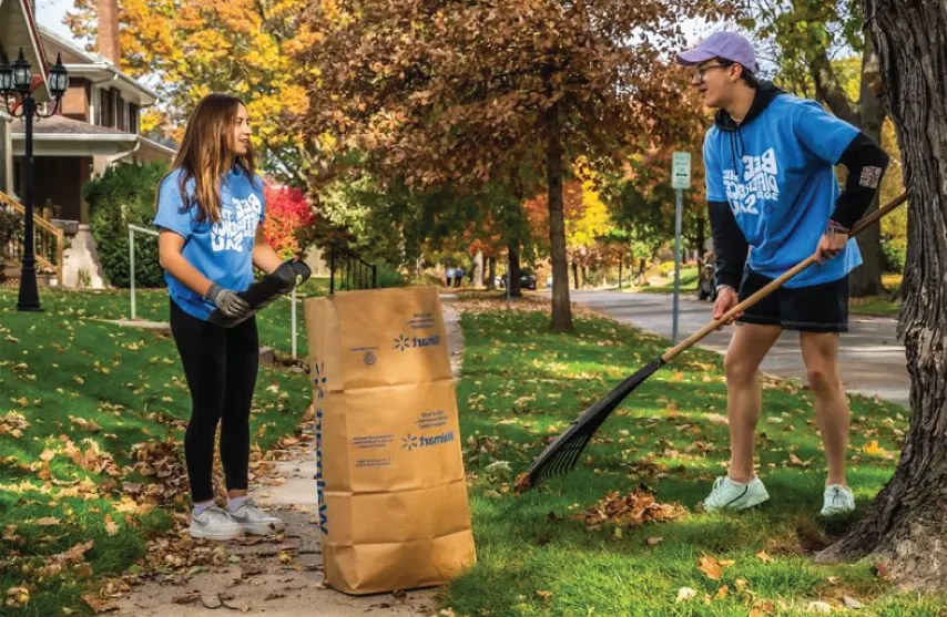 Two students raking in a neighbors yard